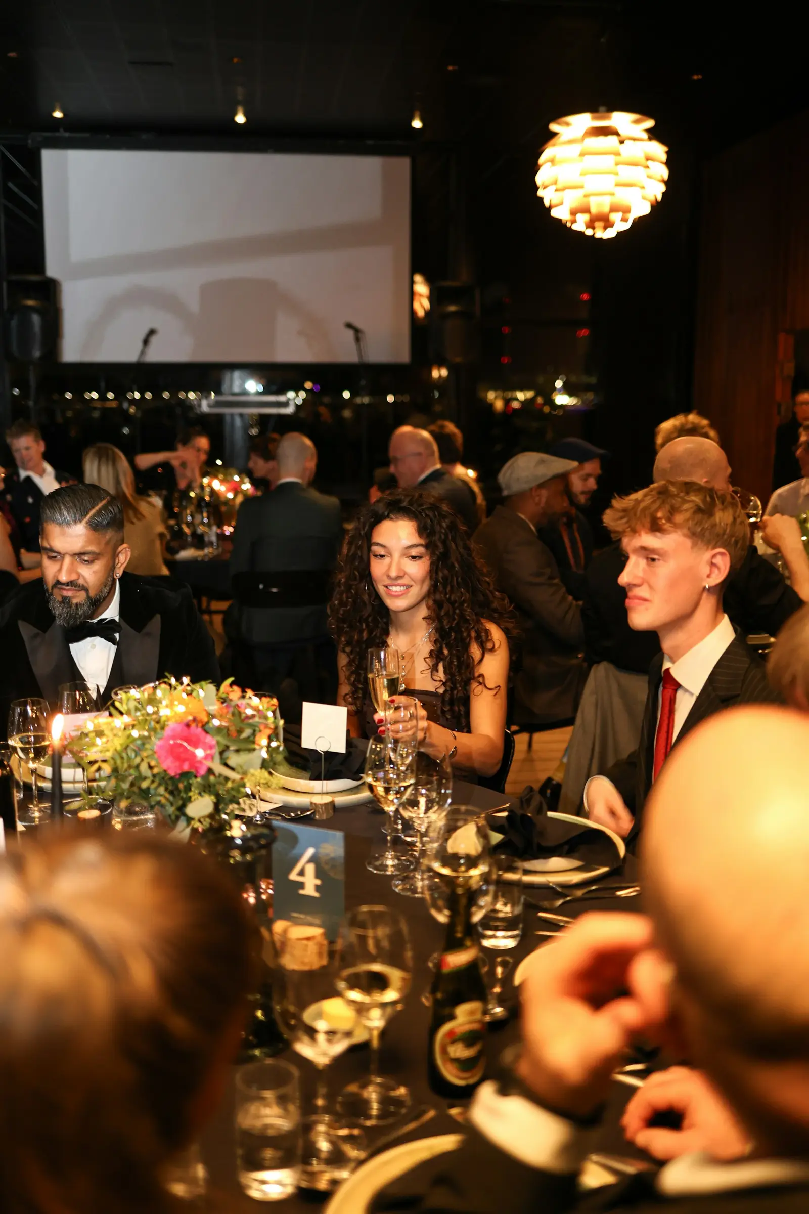Guests in black tie seated at a candle-lit gala dinner table